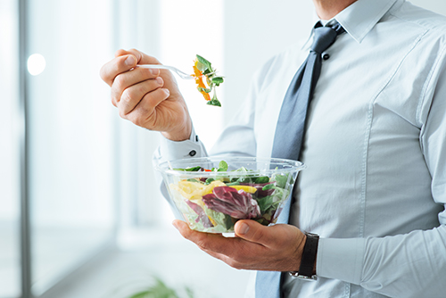 Homme d’affaire debout et mangeant une salade